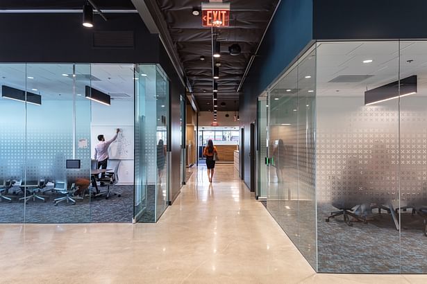 This view down corridor between two meeting rooms provides a view to the exterior and simultaneously highlights the beneficial effects of transparency used throughout the project.