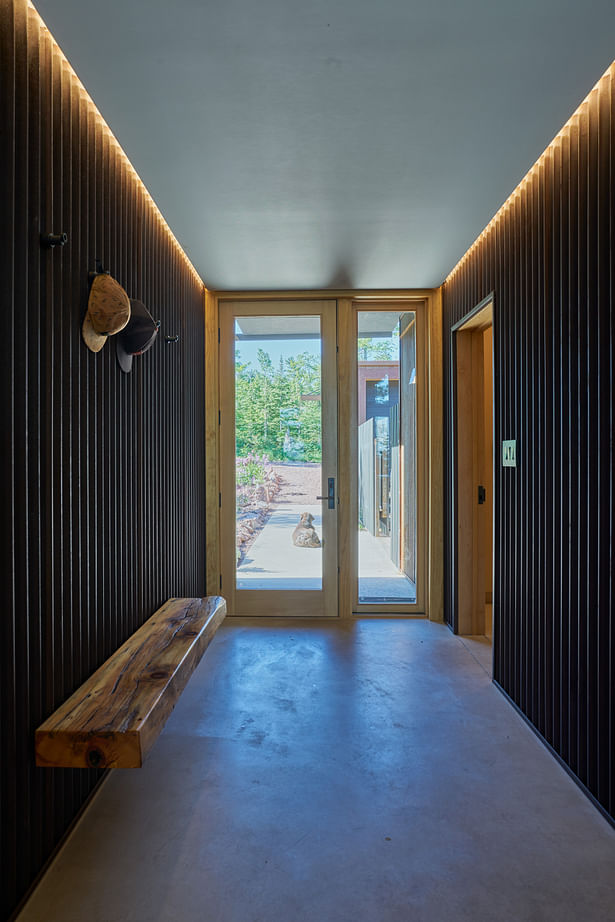 Black painted corrugated metal and recessed cove lighting emphasize the hallway axis of the home. Photos by Kes Efstathiou