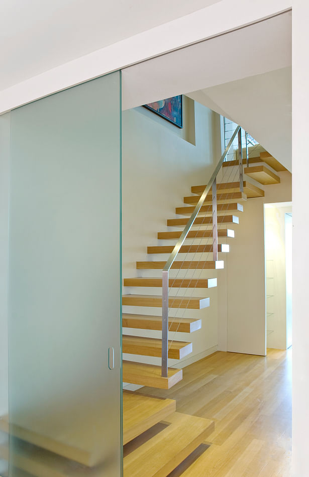 The cantilevered stair is the centerpiece of this apartment combination and renovation. The floating oak treads match the oak floors but contrast with the exquisite stainless steel cable railing. The visual simplicity of the stair belies the complexity of the structural and detail coordination needed to achieve this degree of minimalism.
