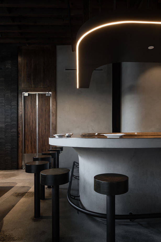The overhead light, the soft edges of the bar, and the warm color palette make for a comfortable seating area, resulting in a warm and unostentatious environment that is full of Japanese elements and tradition.
