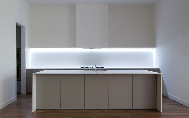 Enhancing the sculptural design of the kitchen, is a strip of LED lights just below the one and only line of open shelving against the wall.