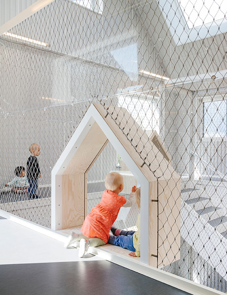 The interior of the kindergarten is bright and clutter-free. Plexiglas ensures that the children may safely play along the atrium's balconies.