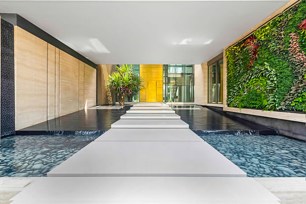 The home's grand entrance features a reflecting pond with floating stairs surrounded by a cascading water feature on one side and a living green wall on the other.