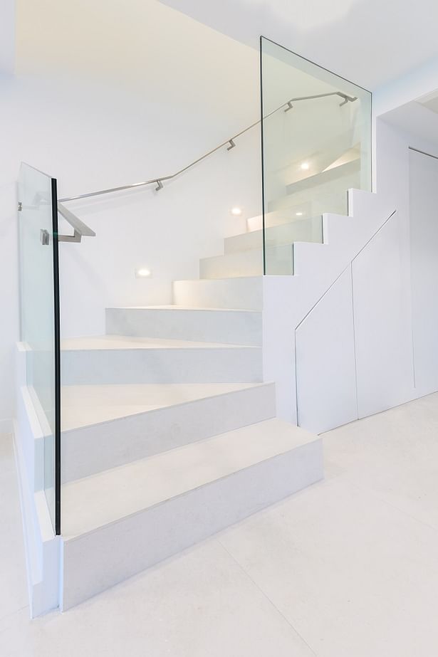 A stainless steel flat-bar handrail was installed directly onto the glass panel, which then transitions to becoming wall mounted.