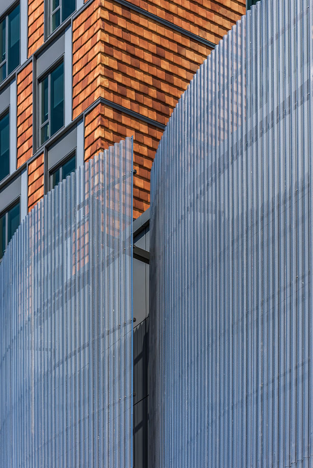 The exterior of the residential tower is clad in a vertical terracotta tile rainscreen, its variegated tones lightening as the height of the building increases. A curved screen made of perforated corrugated stainless steel panels adds contrast and a veil-like elegance to the façade of the performance wing. Photo credit: Peter Vanderwarker