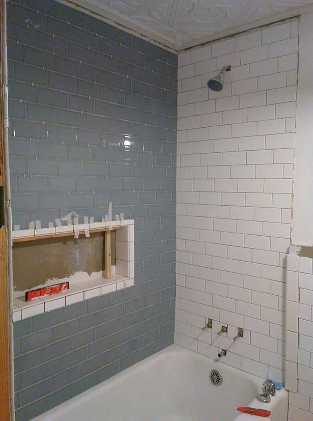 Plywood was replaced with backerboard; new subway tile installed around the existing cast iron tub. Tub enamel was cleaned & repaired.
