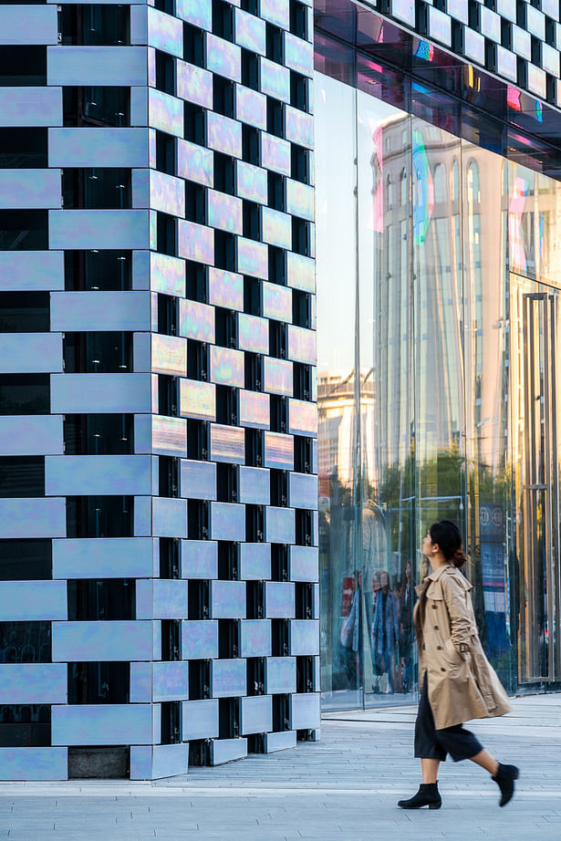 The building is wrapped in a pearlescent ceramic façade that at different times appears either grey or colourful, creating a subtle façade that does not need large LED screens to stand out and catch the attention of the passers-by. Hand-glazed in China, these tiles were made by applying three layers of glaze to the ceramic, and firing at a different temperature each time.