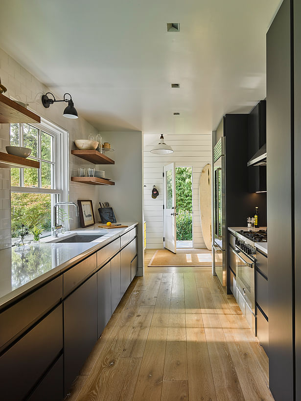 A sleek kitchen with natural wood floors and shelves.