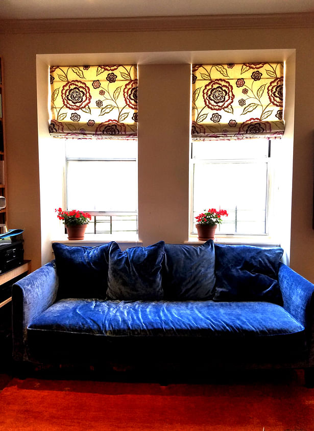 New dark, blue velvet sofa slipcover. Floral patterned roman shades.
