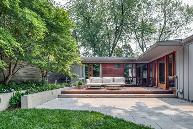 The deck’s patio area nests into the L-shape of the house, creating a courtyard-like sense of enclosure