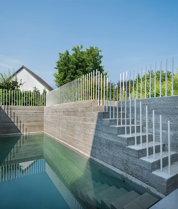 The pool with counter current swim system is framed by rammed concrete walls above water level. (photo: Gui Rebelo / rundzwei Architekten)