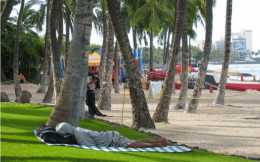 A homeless individual sleeps on the beach in Waikiki. Credit: Cathy Bussewitz / AP Images