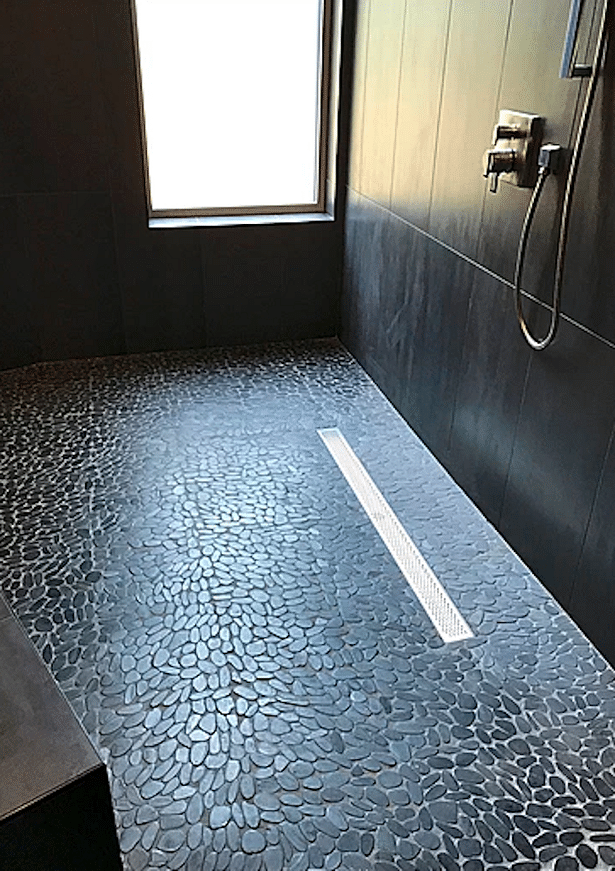 A linear drain complements the pebble tile floor in the master shower.