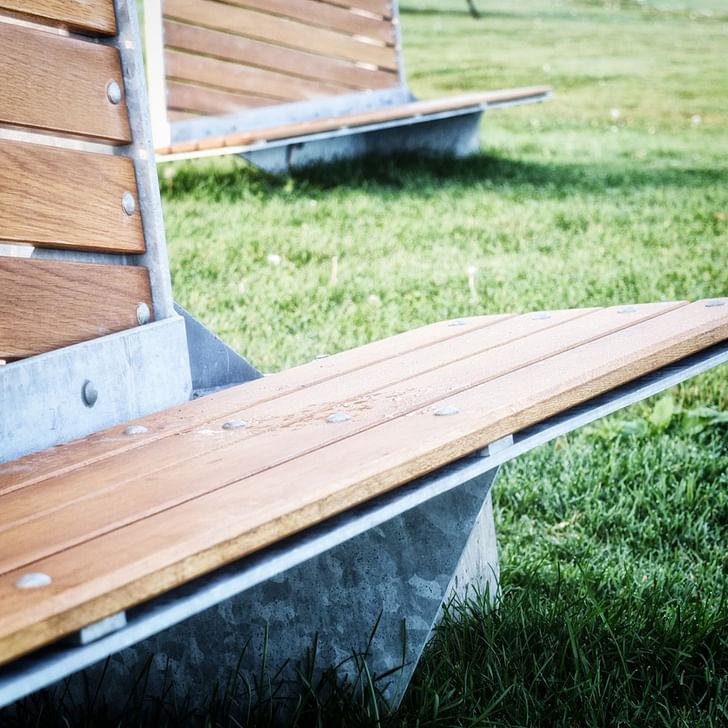 The bench design combines white oak planks with concrete and metal. 