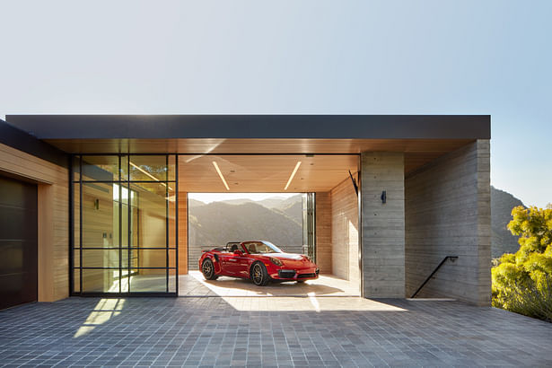 Minimal in form, the layered design respects the home’s surroundings, catering to the entrepreneurial homeowners’ need as both a full-time residence and part-time wellness retreat. The show garage, shown here, doubles as an open-air yoga studio. (Roger Davies Photography)