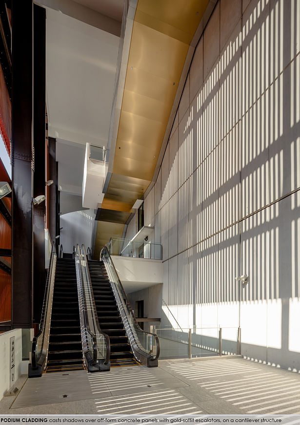 Podium cladding that casts shadows over off-form concrete panels with gold so-ffit escalators