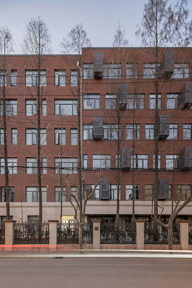 The east facade along the street (left) when the evening lights are lit. 