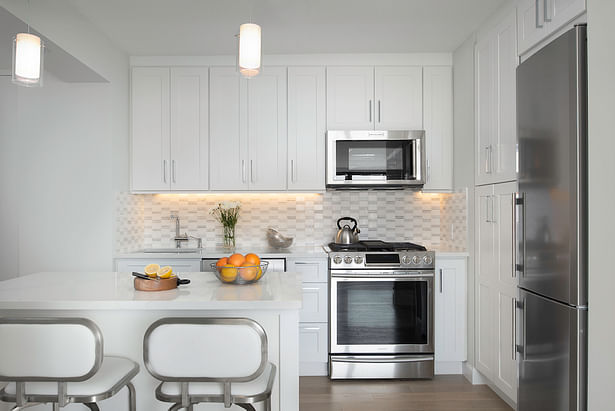 Newly improved open kitchen with island, soffit for lighting, american appliances, thermofoil raised panel cabinet doors and milestone countertops and marble backsplash