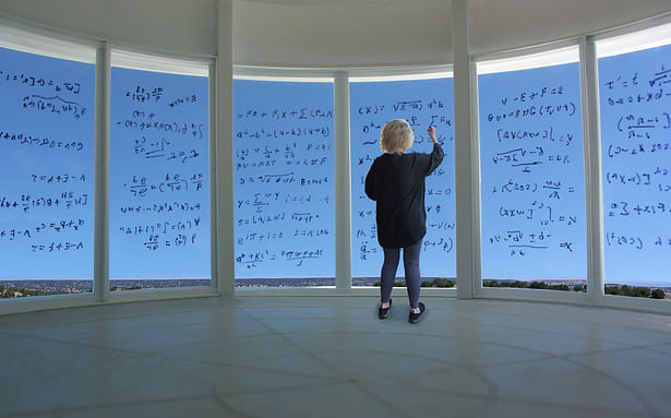 Detail view of a researcher writing equations on the curved glass panels.