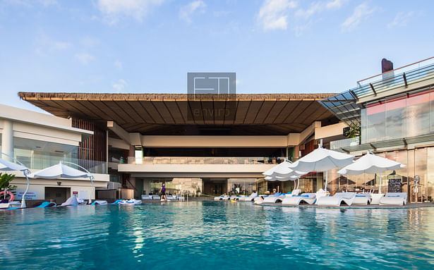 Sheraton kuta bali swimming pool expansive view to lobby area featuring colossal cantilevered biodegrable synthetic alang alang roof