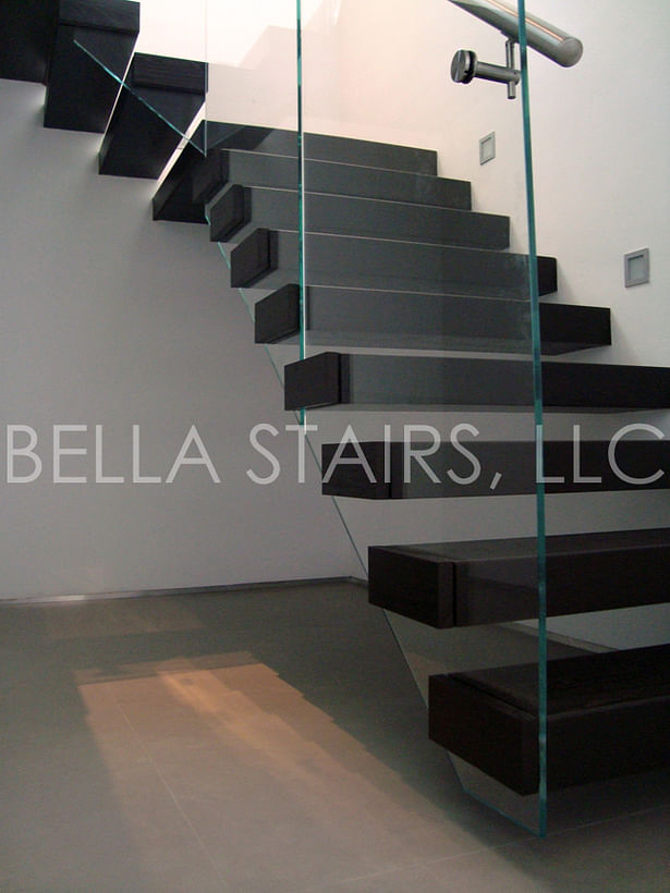 Glass railings are anchored to each tread using stainless steel standoffs and covered with a wood cap on each tread.