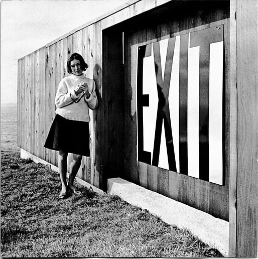 Barbara Stauffacher Solomon beside an enamel exit sign at Lawrence Halprin’s house at The Sea Ranch