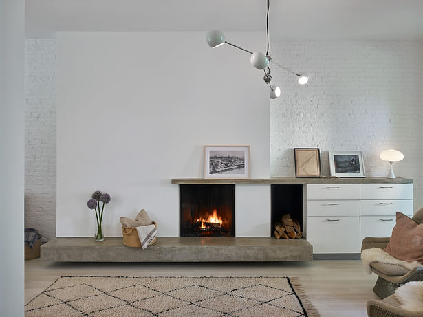 The fireplace with concrete slab front adds a subtle contrast to the white oak floors.