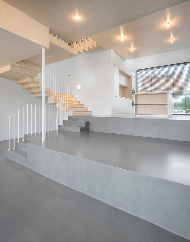 On the lower living level starts the central stair. The split-level living space transitions seamlessly into the kitchen level with built-in kitchen and counter to the front. (photo: Gui Rebelo / rundzwei Architekten)
