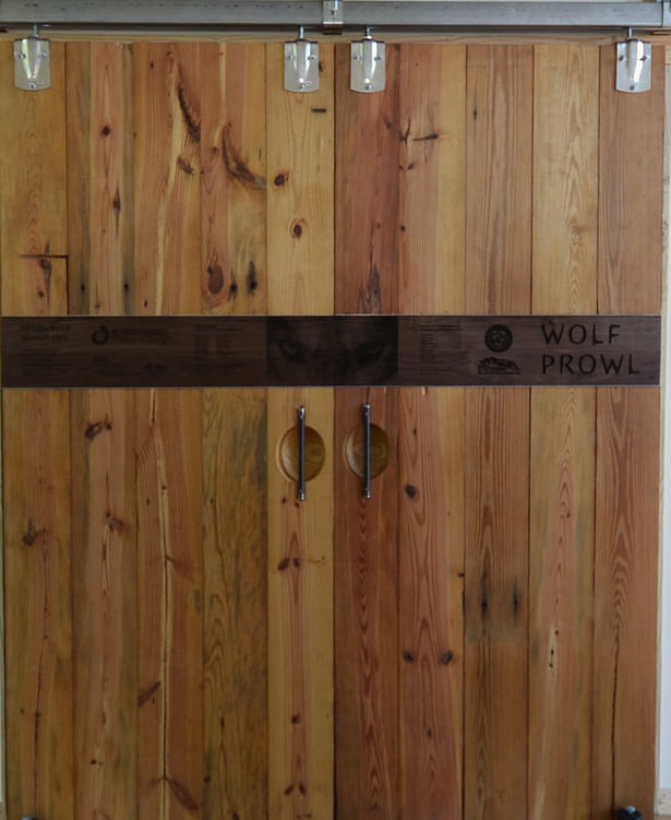 Laser-engraved sliding walnut doors lead to the interior of the larger shed volume.