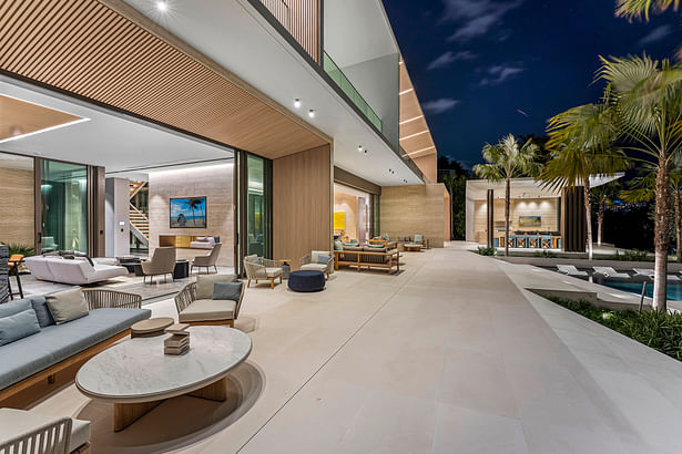 Tall glass doors open out to the pool, outdoor kitchen, and yacht dock.