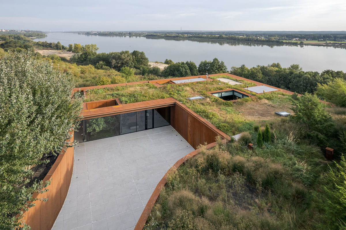 Camouflaged within nature, this Polish home sits in harmony with its riverside landscape