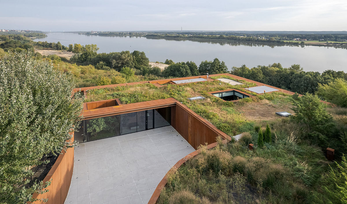 Camouflaged within nature, this Polish home sits in harmony with its riverside landscape