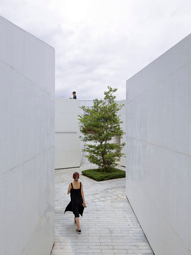 Intersecting paths and white terrazzo materials give a natural and rough facade.