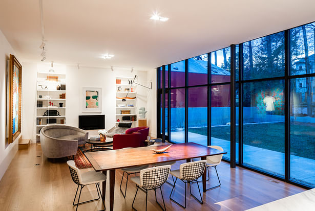 Looking from the new kitchen at one end to the fireplace and built-in display shelves at the other. The glass wall provides views of the backyard and the architecturally diverse neighborhood.