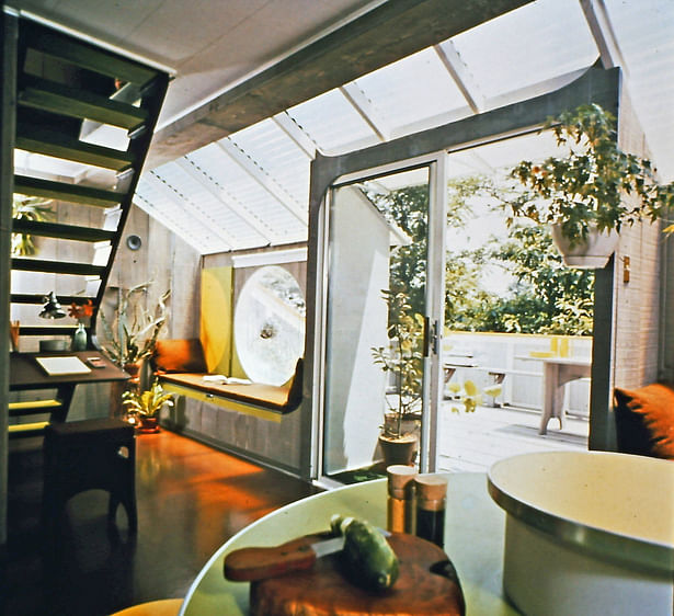 Interior view of the house showing a bubble window, sliding glass door, one of the seats in the closed position, and the corrugated fiberglass glazed roof section. 