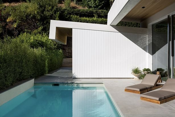 'Outside, a tidy backyard patio features the original pool and spa. The home's crisp white facade provide a fresh backdrop for relaxing in the sun.'