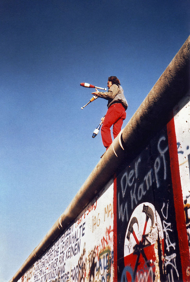 Man juggling atop the Berlin Wall. Image: Wikipedia