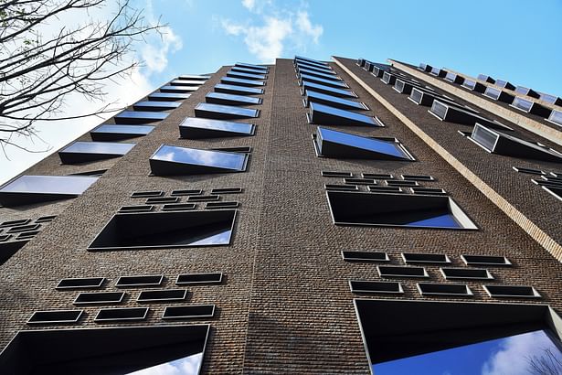 Protruding triangular windows on a solid brick façade