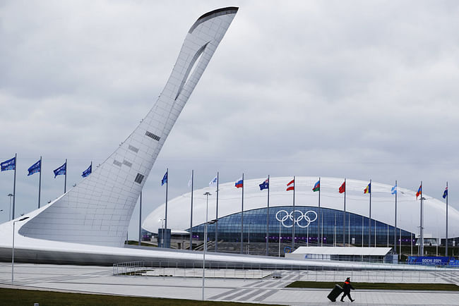 A worker walks past the Olympic torch and the Bolshoy Ice Dome in the Olympic Park as preparations continue Thursday ahead of the Sochi Winter Games. Russia has spent $50 billion on the 2014 games — the most expensive in history. (NPR/Pavel Golovkin/AP)