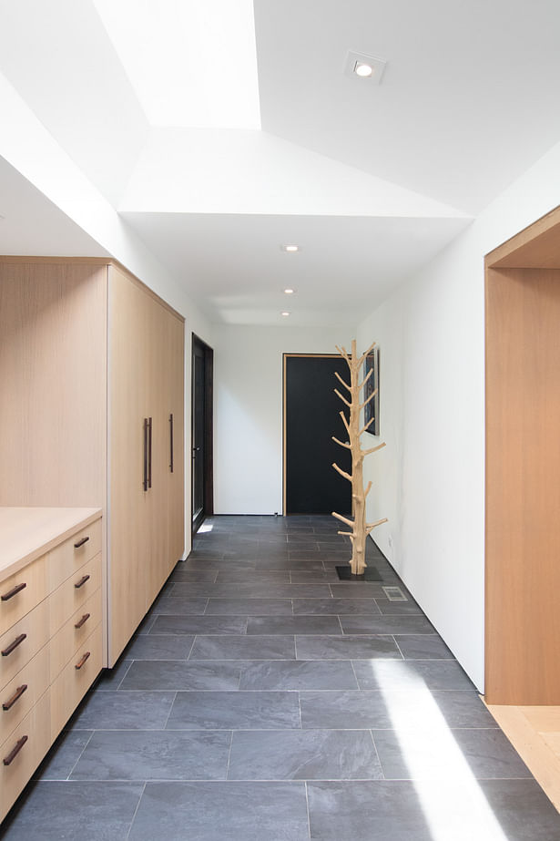 The new entry hall serves as an informal mudroom entry for the family, off the carport. Slate-look porcelain tile and white oak cabinetry provide a natural, muted palette for the hustle-bustle of a young family.