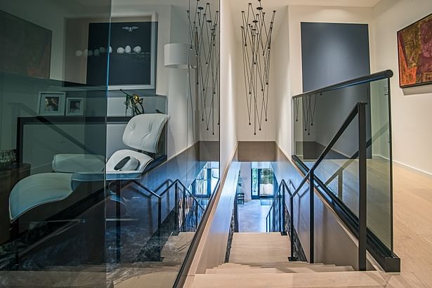 A matte black flat-bar handrail was also installed on the staircase where it is met with a tinted glass guardrail on the second floor.