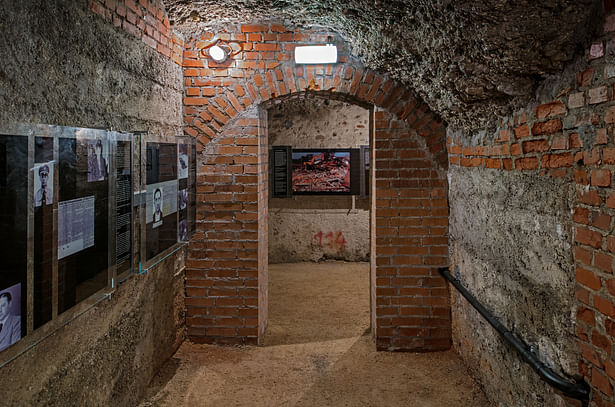 Perpetrator Room: The exit from the room is narrowed by means of solid stone pillars under the load-bearing brick belt. These redundant “supports” built in place of the former 25 cm partition wall emphasise the impression of heaviness and oppression. 