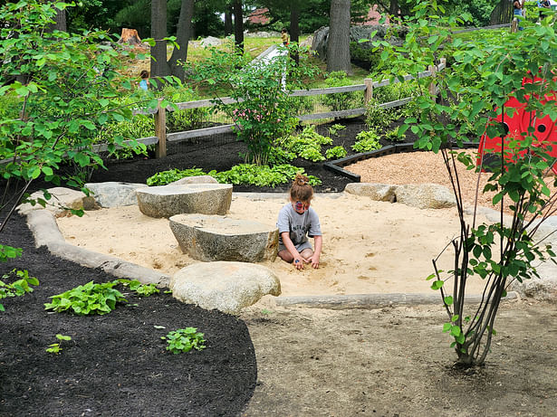 A kid playing in the sand play area.
