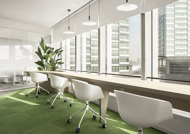 Some workplaces are presented in the form of open compartments near the curtain wall with green plants.