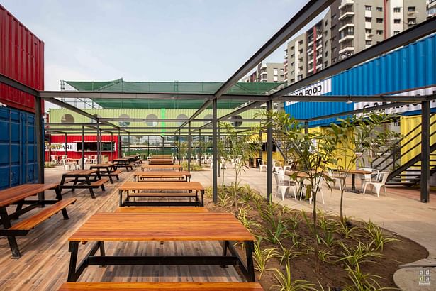 An expansive outdoor food plaza utilizes a collage of containers repurposed as food outlets which have been arranged to form an alfresco dining experience for end users. The pops of colours on the containers add character to the exteriors. 
