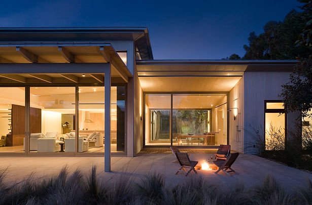 The house is designed to connect the inside to the beautiful natural setting outside. A large deck, partly covered with an awning, extends from the living room. To the side is a fire pit for informal outside gathering. Beyond is a wall-mounted shower for returning beach-goers.
