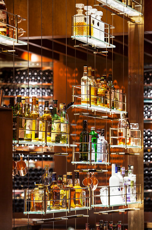 Detail: Floor-to-ceiling structurally tensioned bronzed stainless steel cable, electrified bottle shelving.