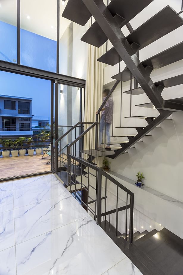 The largesse of this space has been further realized with a play of proportions, by providing full height glass screen which showcases the sculptural sparkling grey metal staircase; gracing the double height volume. The glass screen allows the stairwell to engulf bundles of natural light, which then bathe the interior spaces, such as the main living area, in a balanced light through the cut-outs.
