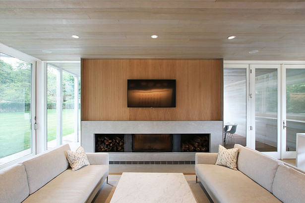 The Fireplace Wall in the Living Space is Composed of Black Steel Log Niches, Gray Marble, and White Oak