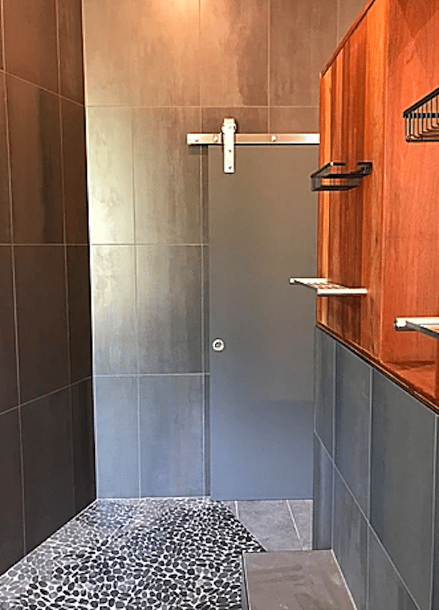 A sliding barn door provides privacy for the 'water closet' in an otherwise open space.